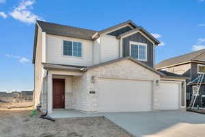 Craftsman inspired home with stone siding, board and batten siding, concrete driveway, and roof with shingles