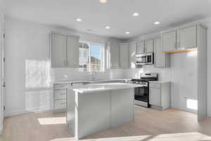 Kitchen with stainless steel appliances, gray cabinets, light wood-style floors, a kitchen island, and recessed lighting