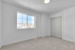 Unfurnished bedroom featuring a textured ceiling, a closet, and light colored carpet