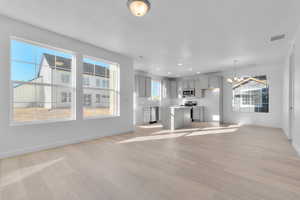 Unfurnished living room with a chandelier, light wood finished floors, and recessed lighting
