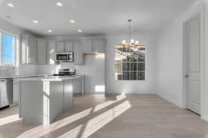 Kitchen featuring gray cabinetry, recessed lighting, appliances with stainless steel finishes, a kitchen island, and a chandelier