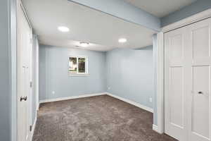 Unfurnished bedroom with dark colored carpet, recessed lighting, and a closet