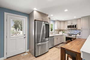 Kitchen with stainless steel appliances, gray cabinetry, tasteful backsplash, light wood-style floors, and recessed lighting