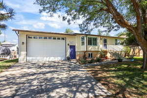 View of front facade with driveway, an attached garage, and a front lawn