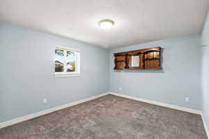 Carpeted empty room with baseboards and a textured ceiling