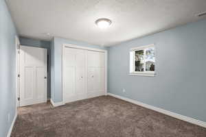 Unfurnished bedroom with carpet, a textured ceiling, and a closet