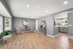 Living area with light wood-style floors and recessed lighting