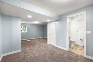 Basement with light carpet, a textured ceiling, and recessed lighting