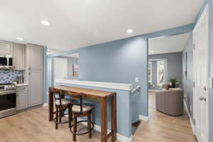 Kitchen featuring gray cabinetry, light wood-style floors, appliances with stainless steel finishes, and recessed lighting