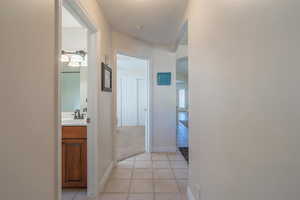 Corridor to secondary bath & bedrooms with light tile patterned flooring and arched walkways