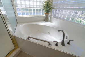 Full bath featuring healthy amount of natural light, a jetted tub, a stall shower, and tile patterned floors