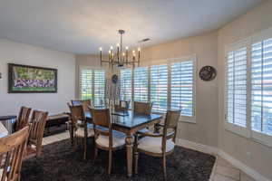Dining area with light tile patterned floors, a chandelier, and a textured ceiling