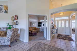 Tiled foyer entrance with arched walkways, a high ceiling, and ornamental molding.