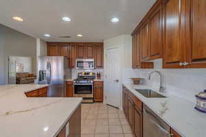 Kitchen featuring a textured ceiling, stainless steel appliances, light quartz countertops, light tile patterned floors, and recessed lighting