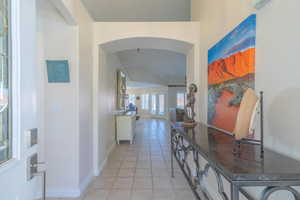 Entry hall with arched walkways, light tile patterned floors, and ornamental molding
