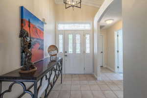 Entryway featuring light tile patterned floors, arched walkways, and a chandelier