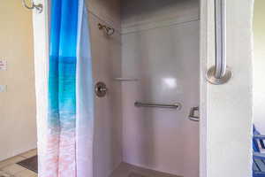 Full bath with a stall shower, a textured wall, and tile patterned flooring