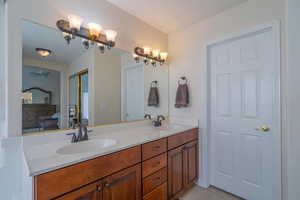 Primary Bathroom featuring double vanity, light tile patterned flooring, ensuite bathroom, and a ceiling fan