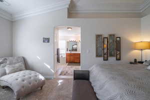 Primary Bedroom with ornamental molding, arched walkways, ensuite bathroom, and light colored carpet