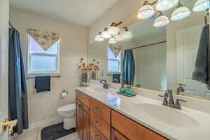 2nd Bathroom with light tile patterned floors, plenty of natural light, double vanity, and a shower with shower curtain