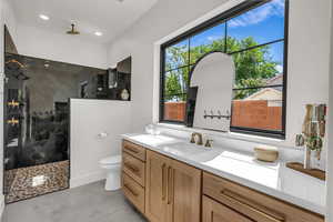 Bathroom featuring a walk in shower, vanity, and recessed lighting