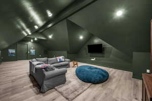 Home theater room with light wood-type flooring and lofted ceiling