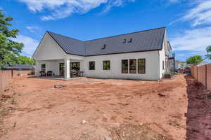 Rear view of house featuring a fenced backyard, a patio, a metal roof, and stucco siding