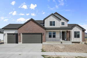 View of front of property featuring board and batten siding, a garage, covered porch, concrete driveway, and roof with shingles