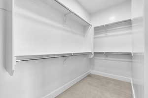 Walk in closet with light colored carpet