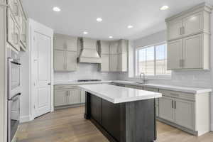 Kitchen featuring gray cabinetry, light wood finished floors, recessed lighting, double oven, and backsplash