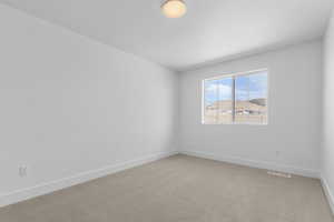 Empty room featuring light colored carpet and baseboards