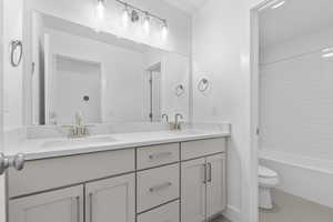 Bathroom featuring double vanity, bathing tub / shower combination, and light tile patterned floors