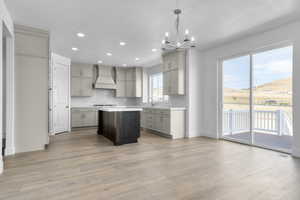 Kitchen with gray cabinets, tasteful backsplash, custom exhaust hood, light wood-style flooring, and recessed lighting