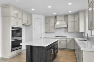 Kitchen featuring recessed lighting, light stone countertops, stainless steel appliances, a kitchen island, and light wood-style flooring