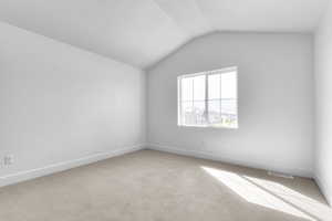 Empty room with lofted ceiling and light colored carpet