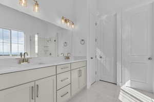 Bathroom featuring a shower stall, double vanity, and light marble finish flooring