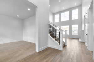 Entrance foyer with recessed lighting, stairway, light wood-type flooring, and a high ceiling