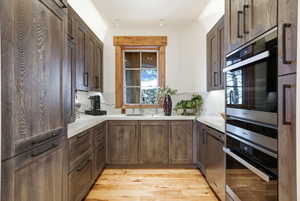 Kitchen with light wood-type flooring, dark brown cabinets, and stainless steel appliances