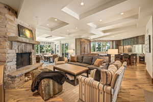 Living room featuring plenty of natural light, light wood-type flooring, coffered ceiling, a fireplace, and beam ceiling