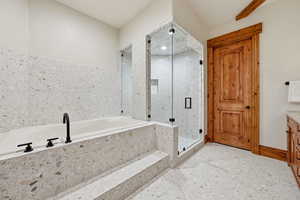 Bathroom featuring a garden tub, vanity, and a marble finish shower
