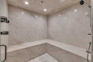 Full bath featuring a marble finish shower and recessed lighting