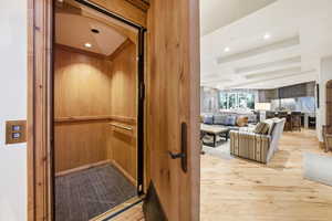 Detailed view of coffered ceiling, beamed ceiling, recessed lighting, wood finished floors, and elevator