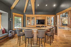 Indoor wet bar featuring recessed lighting, light wood-style flooring, beamed ceiling, and glass insert cabinets