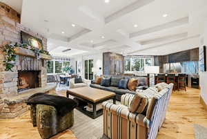 Living area with light wood-style flooring, coffered ceiling, a fireplace, and beamed ceiling