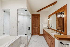 Full bathroom featuring double vanity, a bath, and a marble finish shower