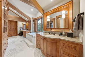Full bathroom featuring a bath, two vanities, light marble finish floors, and recessed lighting