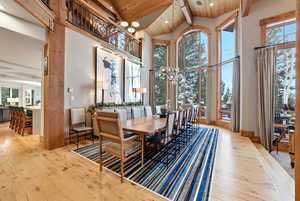Dining area with a chandelier, light wood-style flooring, high vaulted ceiling, a wooden ceiling with exposed beams, and recessed lighting