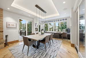 Dining space with a raised ceiling, light wood-type flooring, and recessed lighting