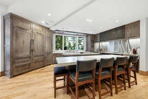 Kitchen featuring light wood-type flooring, a kitchen island, a kitchen breakfast bar, light stone counters, and recessed lighting