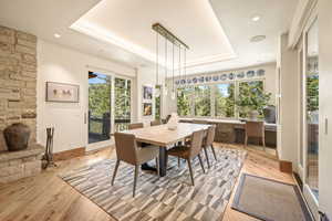 Dining space featuring a raised ceiling and light wood-type flooring